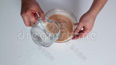 一个男人正在做古拉什酱。 用勺子把番茄酱和酸奶油放入玻璃容器中搅拌..